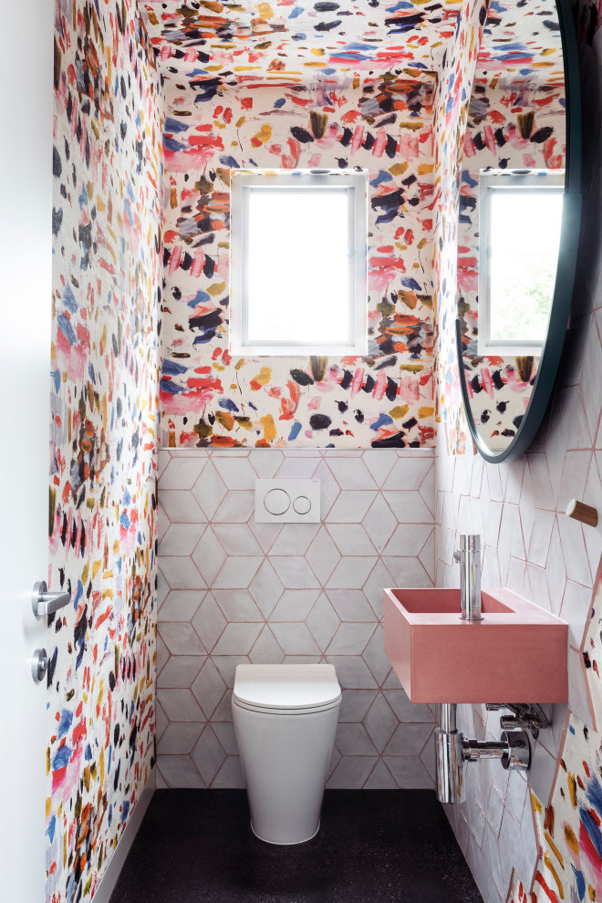 Example of a small trendy white tile and porcelain tile concrete floor, black floor and wallpaper powder room design in Melbourne with a one-piece toilet, multicolored walls, a wall-mount sink, concrete countertops, pink countertops and a floating vanity