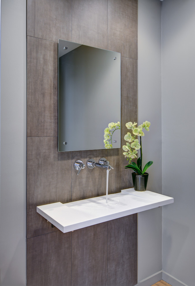 Inspiration for a small contemporary powder room in Detroit with a wall-mount sink, grey walls, solid surface benchtops, brown tile and porcelain tile.