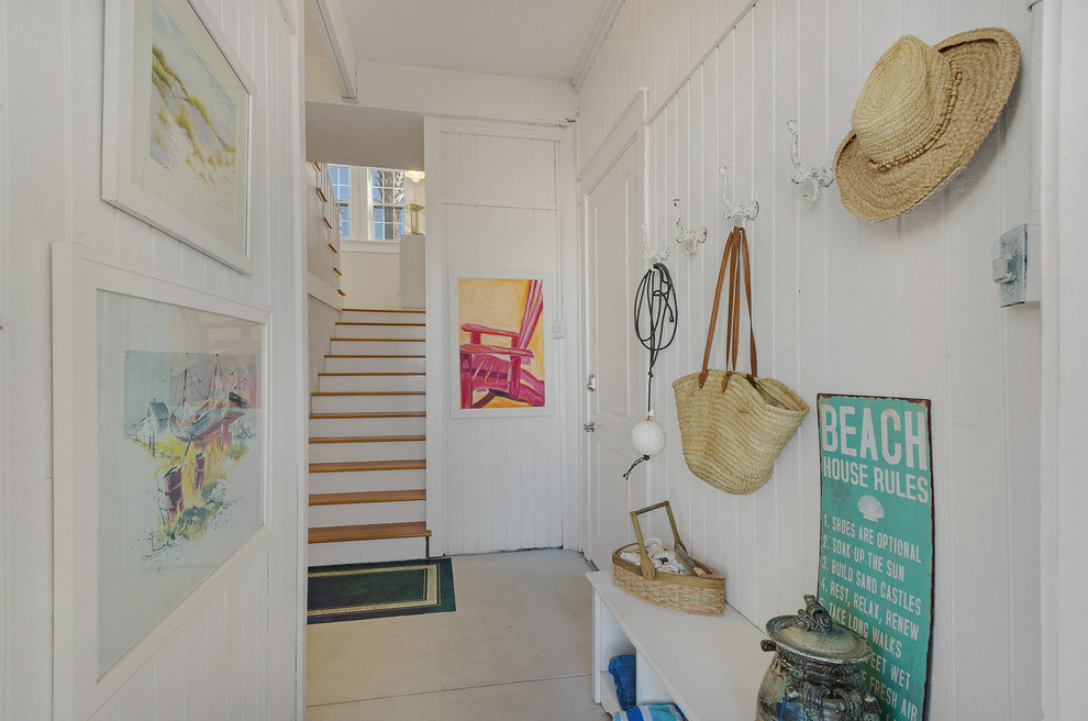 This is an example of a beach style entry hall in Miami with white walls and concrete floors.