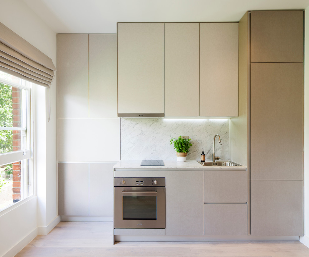 Design ideas for a small contemporary single-wall kitchen in London with a single-bowl sink, flat-panel cabinets, grey cabinets, marble benchtops, stone slab splashback, stainless steel appliances and light hardwood floors.