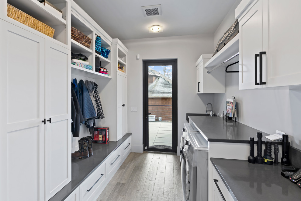 This is an example of a large galley utility room in Seattle with an undermount sink, recessed-panel cabinets, white cabinets, quartzite benchtops, grey walls, a side-by-side washer and dryer and grey benchtop.