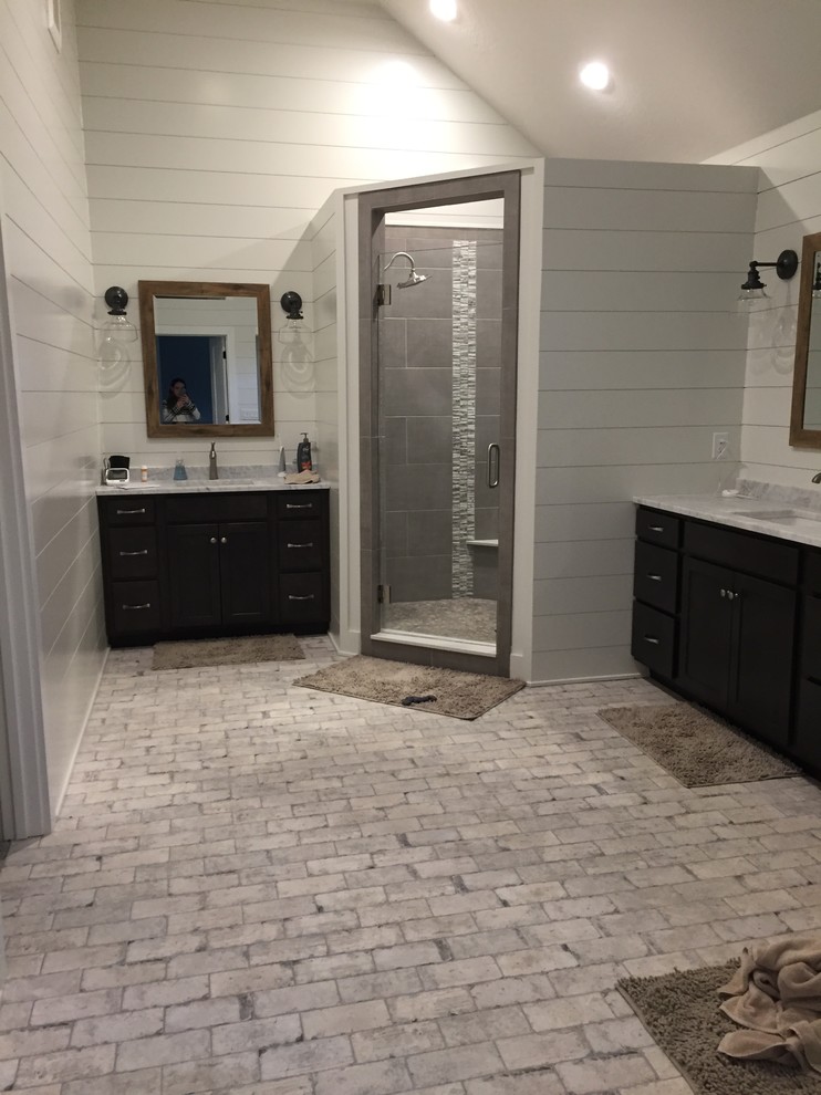 This is an example of a large traditional master bathroom in Indianapolis with black cabinets, a corner shower, gray tile, porcelain tile, white walls, porcelain floors, an undermount sink, marble benchtops, white floor and a hinged shower door.