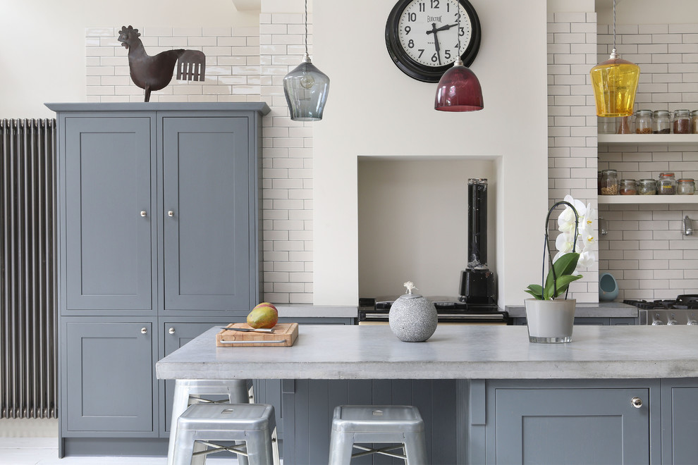This is an example of an eclectic single-wall kitchen in London with grey cabinets, concrete benchtops, white splashback, subway tile splashback and with island.