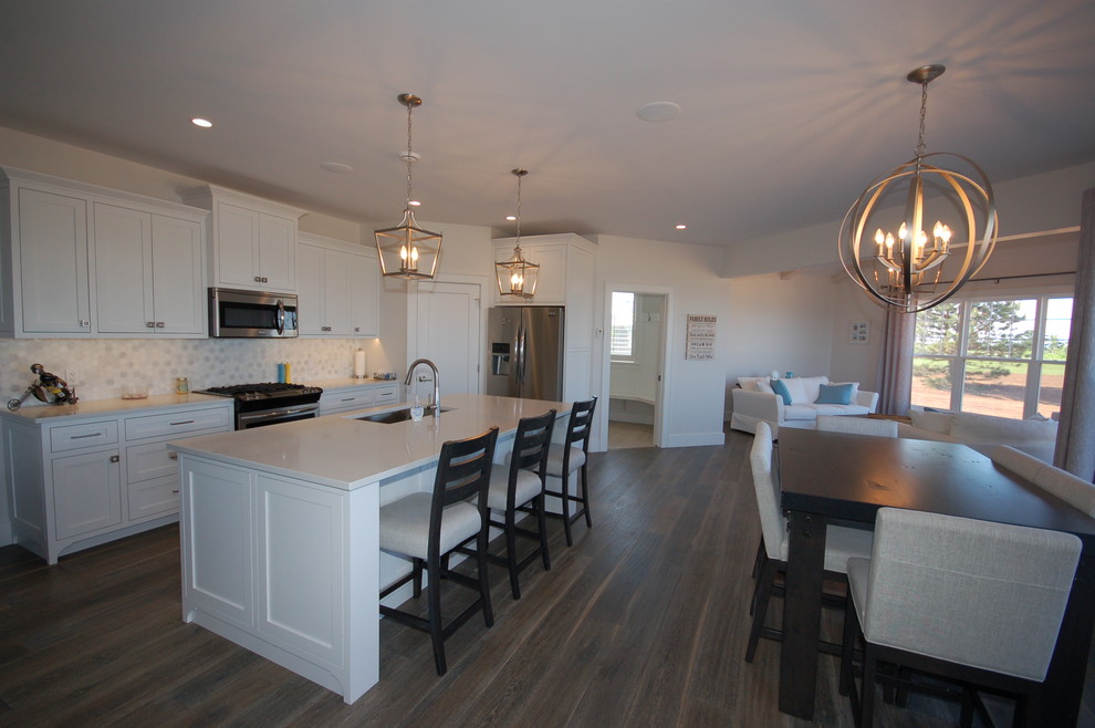 Open concept kitchen - mid-sized transitional l-shaped dark wood floor and brown floor open concept kitchen idea with a single-bowl sink, shaker cabinets, white cabinets, solid surface countertops, white backsplash, stone tile backsplash and an island