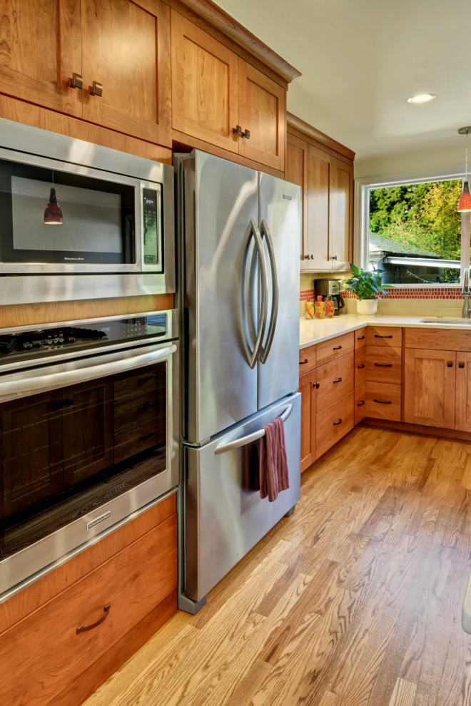 Inspiration for a small l-shaped medium tone wood floor and brown floor eat-in kitchen remodel in Seattle with an undermount sink, shaker cabinets, medium tone wood cabinets, red backsplash, mosaic tile backsplash, stainless steel appliances, an island and white countertops