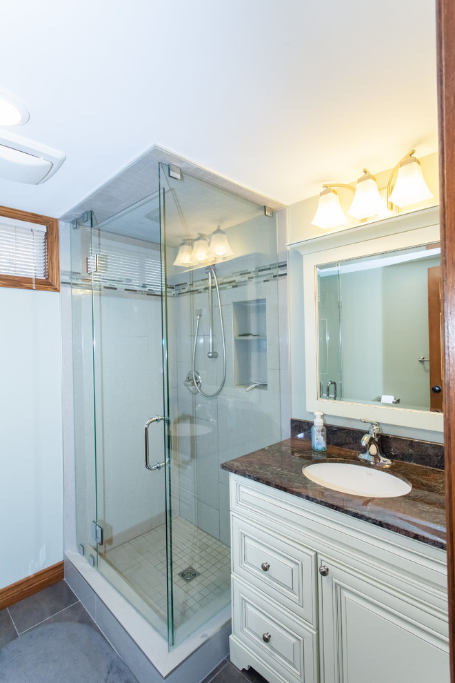Inspiration for a small transitional 3/4 gray tile and porcelain tile porcelain tile and gray floor corner shower remodel with raised-panel cabinets, white cabinets, a two-piece toilet, green walls, an undermount sink, granite countertops and a hinged shower door