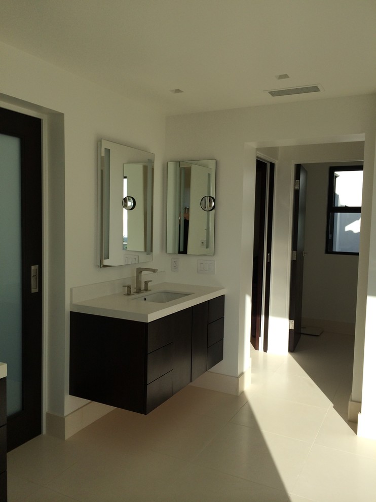 Large mediterranean master bathroom in San Diego with flat-panel cabinets, dark wood cabinets, a freestanding tub, an open shower, a one-piece toilet, beige tile, stone slab, white walls, limestone floors, a drop-in sink and limestone benchtops.