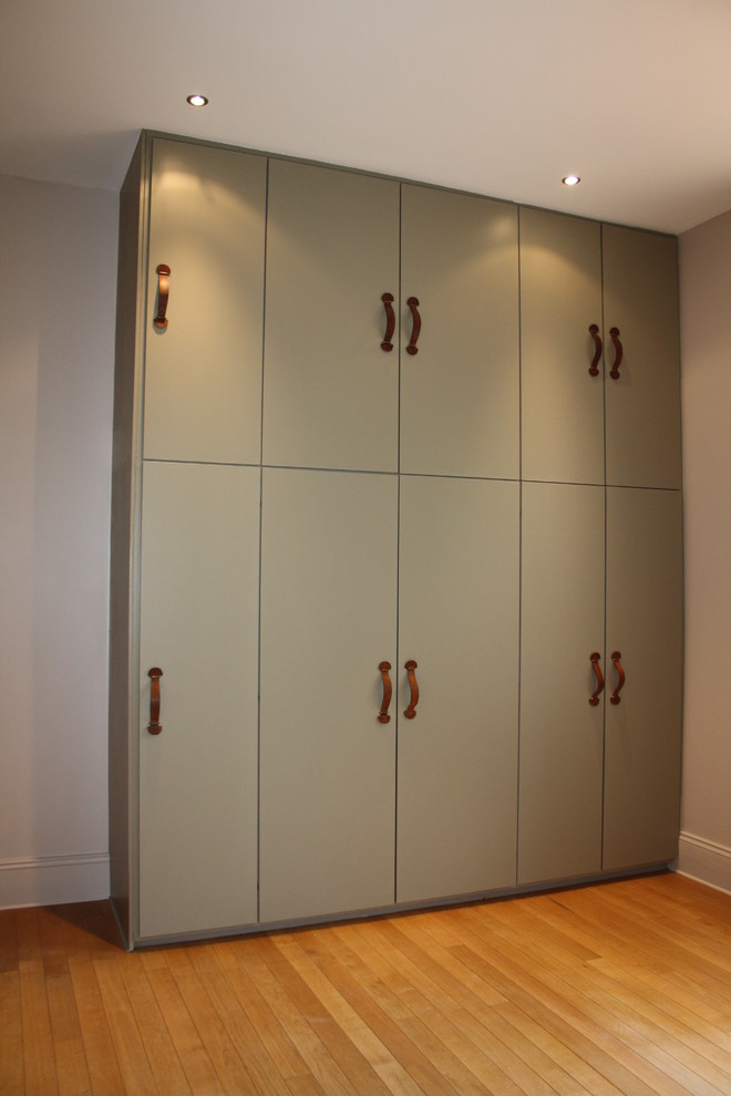 This is an example of a large contemporary gender-neutral walk-in wardrobe in Dijon with flat-panel cabinets, green cabinets and light hardwood floors.