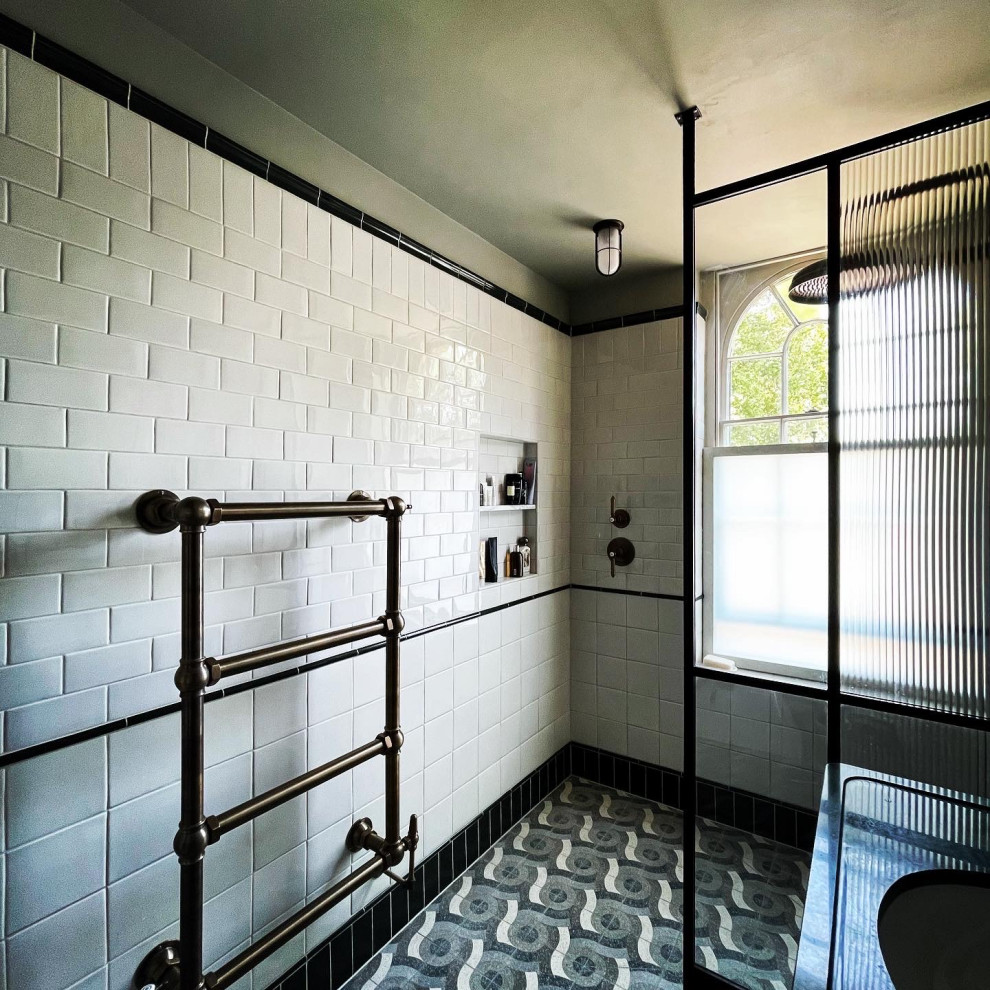 This is an example of a mid-sized traditional 3/4 bathroom in London with an open shower, a wall-mount toilet, green tile, ceramic tile, white walls, cement tiles, a drop-in sink, marble benchtops, multi-coloured floor, an open shower, green benchtops, a single vanity, a freestanding vanity and recessed.