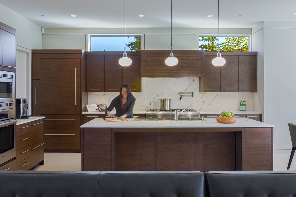 Photo of a contemporary open plan kitchen in Seattle with a triple-bowl sink, flat-panel cabinets, dark wood cabinets, white splashback, stainless steel appliances, with island and white floor.