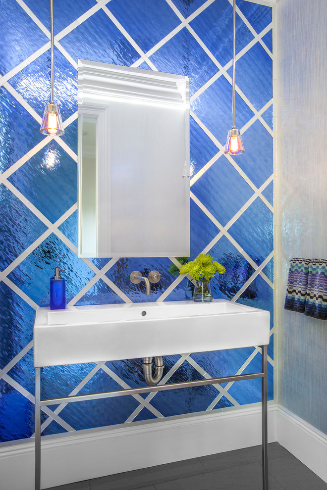 This is an example of a mid-sized transitional powder room in New York with blue tile, glass tile, multi-coloured walls, porcelain floors, grey floor and a console sink.