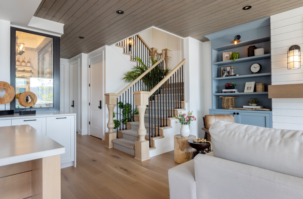 Design ideas for a beach style walk-out basement in Vancouver with a home bar, white walls, light hardwood floors, beige floor and wood.