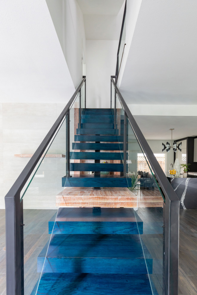 Idées déco pour un escalier flottant moderne de taille moyenne avec des marches en bois, des contremarches en verre et un garde-corps en métal.