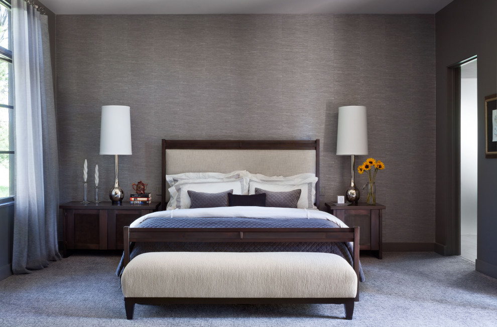 На фото: большая хозяйская спальня в современном стиле с серыми стенами, ковровым покрытием, стандартным камином, фасадом камина из камня, серым полом и обоями на стенах с