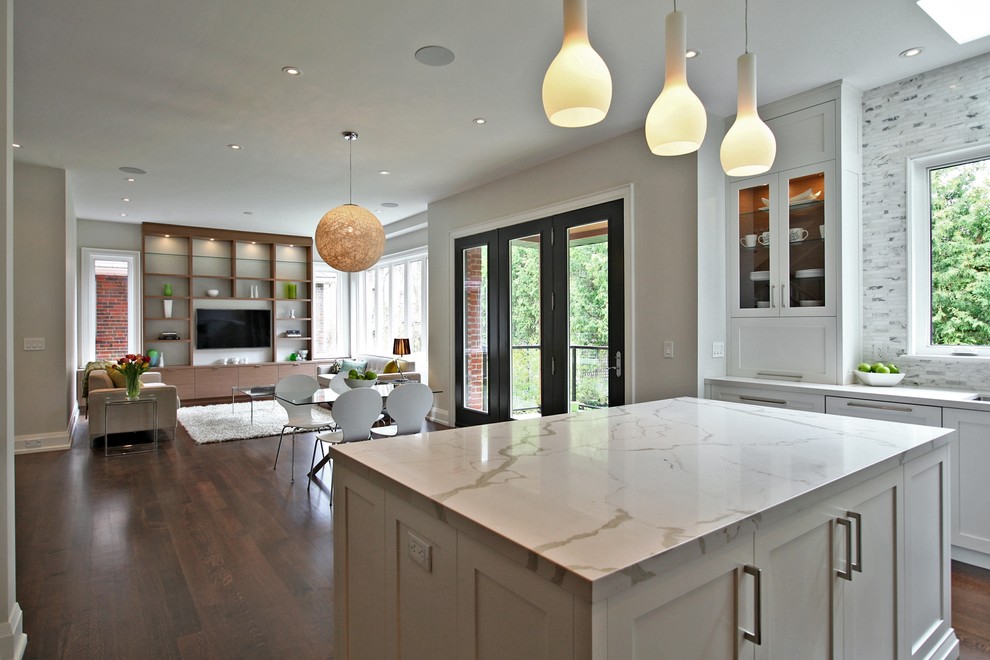 This is an example of a large transitional u-shaped open plan kitchen in Toronto with white cabinets, marble benchtops, white splashback, stainless steel appliances and with island.