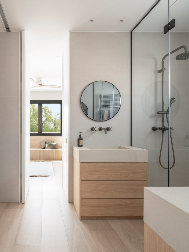 Foto de cuarto de baño único actual con armarios con paneles lisos, puertas de armario de madera clara, ducha a ras de suelo, baldosas y/o azulejos grises, lavabo integrado y encimeras beige