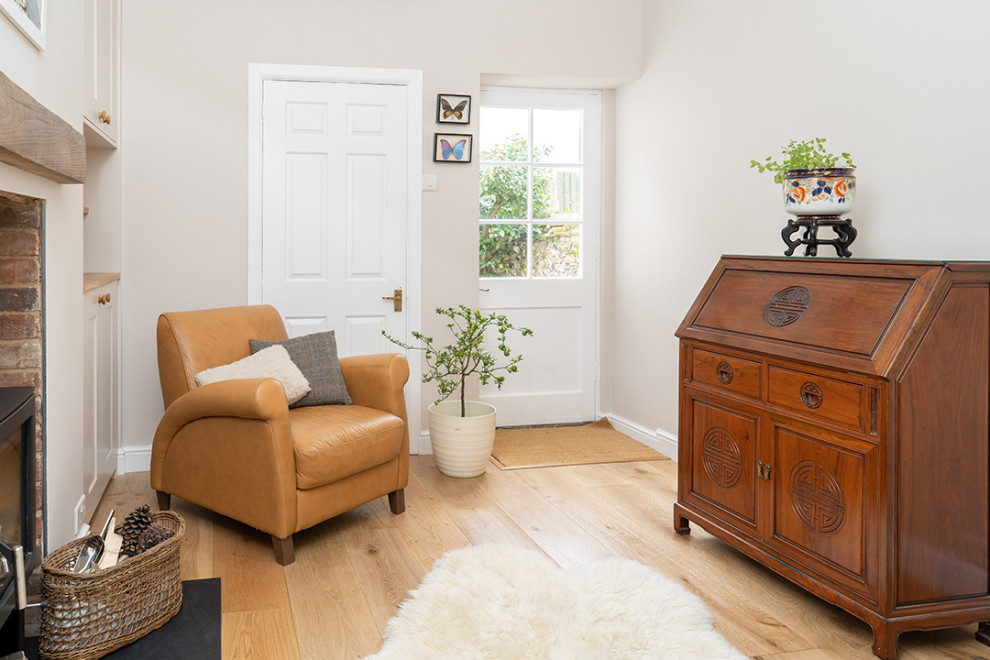 Kleines Klassisches Arbeitszimmer mit braunem Holzboden, Kaminofen und verputzter Kaminumrandung in Sonstige