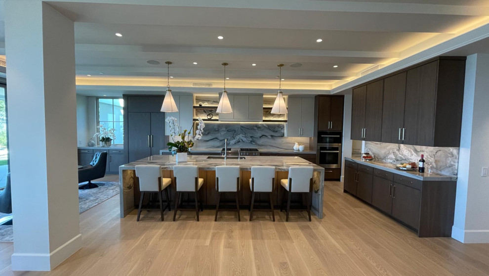 Inspiration for a large transitional l-shaped kitchen pantry in Orange County with an undermount sink, shaker cabinets, white cabinets, granite benchtops, multi-coloured splashback, granite splashback, stainless steel appliances, light hardwood floors, with island, brown floor and multi-coloured benchtop.