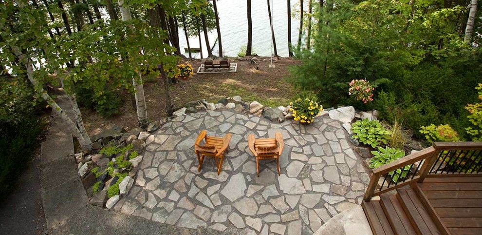 Photo of a large country backyard patio in Ottawa with natural stone pavers and no cover.