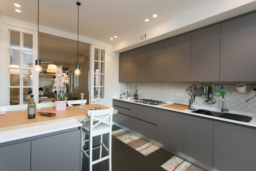 This is an example of a contemporary eat-in kitchen in Rome with dark wood cabinets, marble benchtops, stainless steel appliances, porcelain floors and a peninsula.
