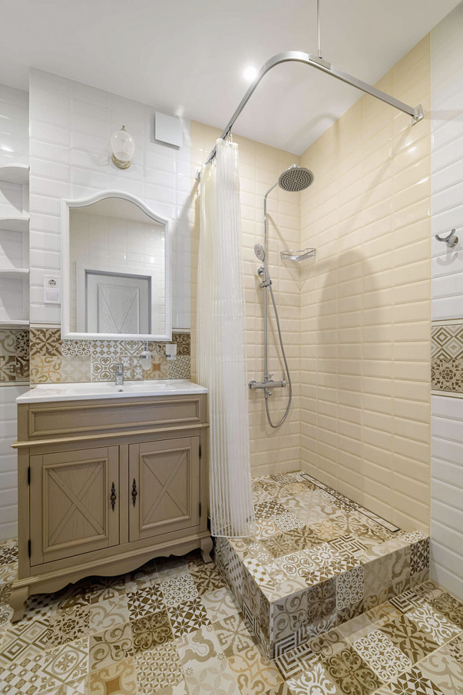 Inspiration for a small country powder room in Other with raised-panel cabinets, beige cabinets, a one-piece toilet, blue tile, ceramic tile, white walls, mosaic tile floors, a drop-in sink, brown floor and a freestanding vanity.