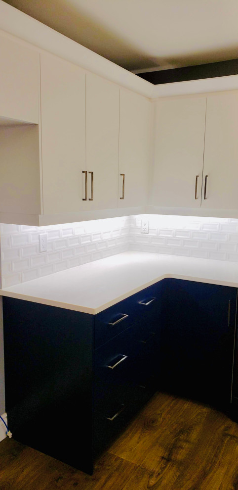 Example of a transitional u-shaped open concept kitchen design with an undermount sink, flat-panel cabinets, white cabinets, quartzite countertops, white backsplash, porcelain backsplash, no island and white countertops