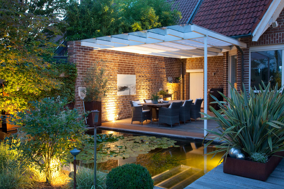 This is an example of a mid-sized contemporary partial sun garden in Dusseldorf with with pond and decking.