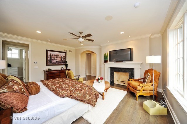 This is an example of a country master bedroom in Chicago with beige walls, medium hardwood floors, a standard fireplace and a tile fireplace surround.