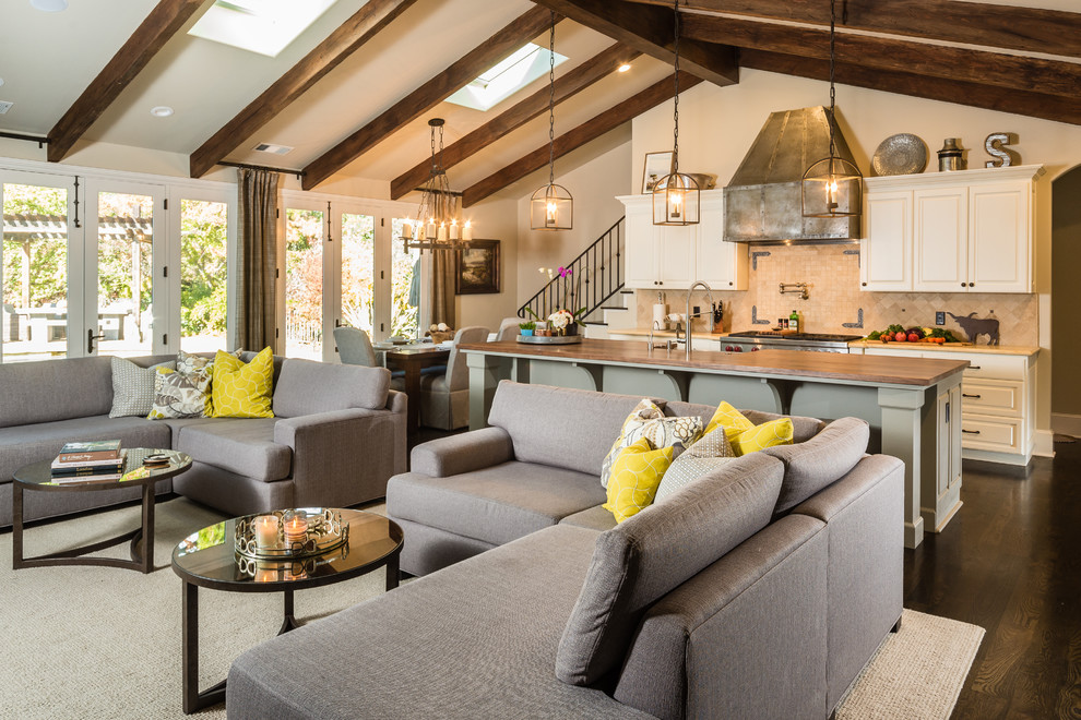 Open concept kitchen - large transitional single-wall dark wood floor open concept kitchen idea with a farmhouse sink, raised-panel cabinets, gray cabinets, wood countertops, beige backsplash, stone tile backsplash, stainless steel appliances and an island