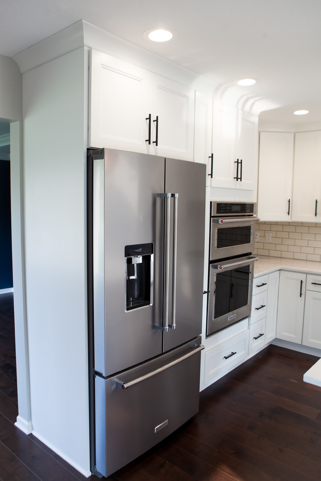 Eat-in kitchen - large transitional l-shaped dark wood floor and brown floor eat-in kitchen idea with an undermount sink, recessed-panel cabinets, white cabinets, quartz countertops, white backsplash, subway tile backsplash, stainless steel appliances and an island