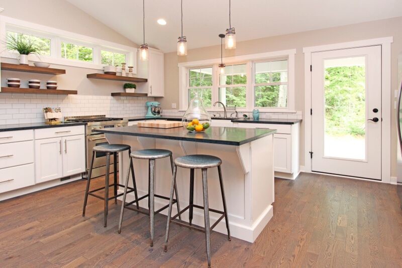 Photo of an eclectic galley kitchen in Grand Rapids with a farmhouse sink, raised-panel cabinets, white cabinets, soapstone benchtops, white splashback, subway tile splashback, stainless steel appliances, medium hardwood floors and with island.