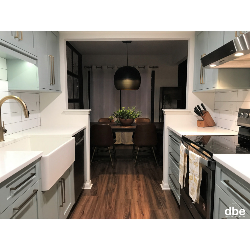 Small transitional galley vinyl floor and brown floor kitchen photo with a farmhouse sink, shaker cabinets, blue cabinets, quartz countertops, white backsplash, subway tile backsplash, stainless steel appliances, no island and white countertops