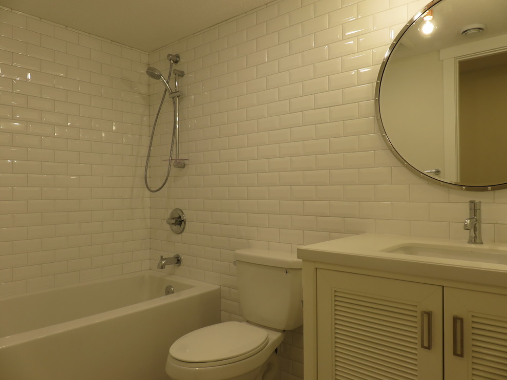 Photo of a small transitional kids bathroom in Calgary with louvered cabinets, white cabinets, an alcove tub, a two-piece toilet, white tile, subway tile, white walls, ceramic floors, an undermount sink, quartzite benchtops and grey floor.