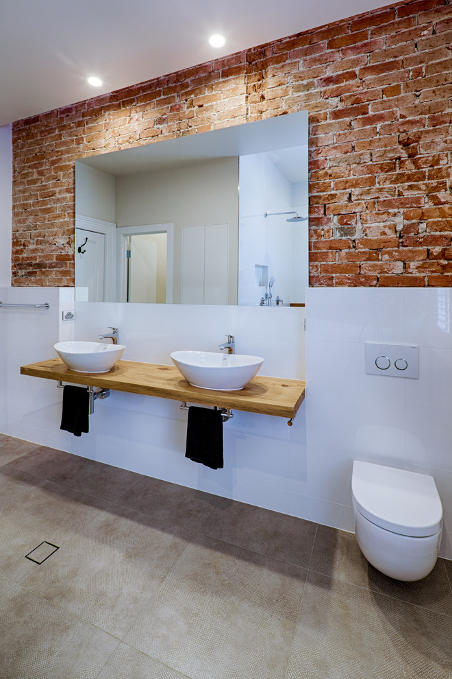 Design ideas for a large industrial 3/4 bathroom in Adelaide with furniture-like cabinets, gray tile, porcelain tile, white walls, porcelain floors, wood benchtops, distressed cabinets, a freestanding tub, an open shower, a one-piece toilet, a wall-mount sink, grey floor, an open shower and brown benchtops.