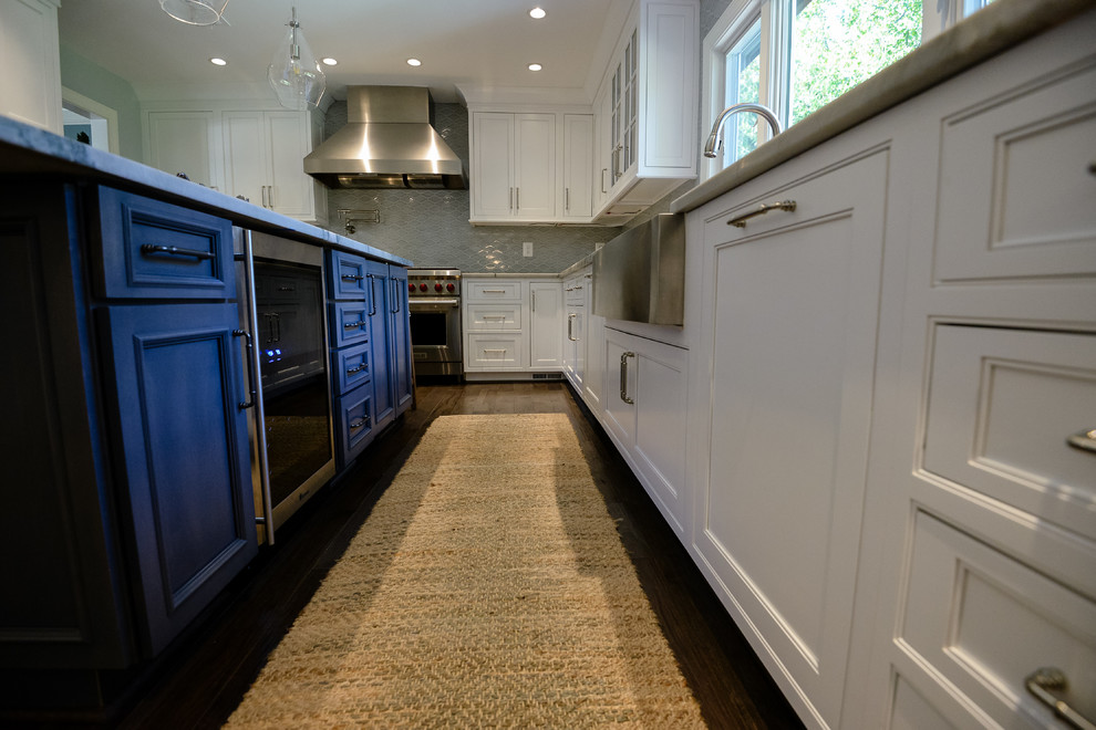 Large transitional u-shaped medium tone wood floor and brown floor eat-in kitchen photo in DC Metro with a farmhouse sink, recessed-panel cabinets, white cabinets, marble countertops, stainless steel appliances and an island