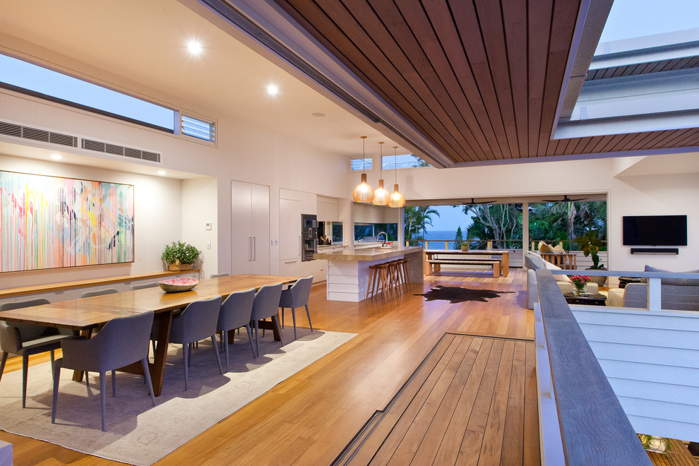 Design ideas for a contemporary open plan dining in Sunshine Coast with white walls, medium hardwood floors and brown floor.