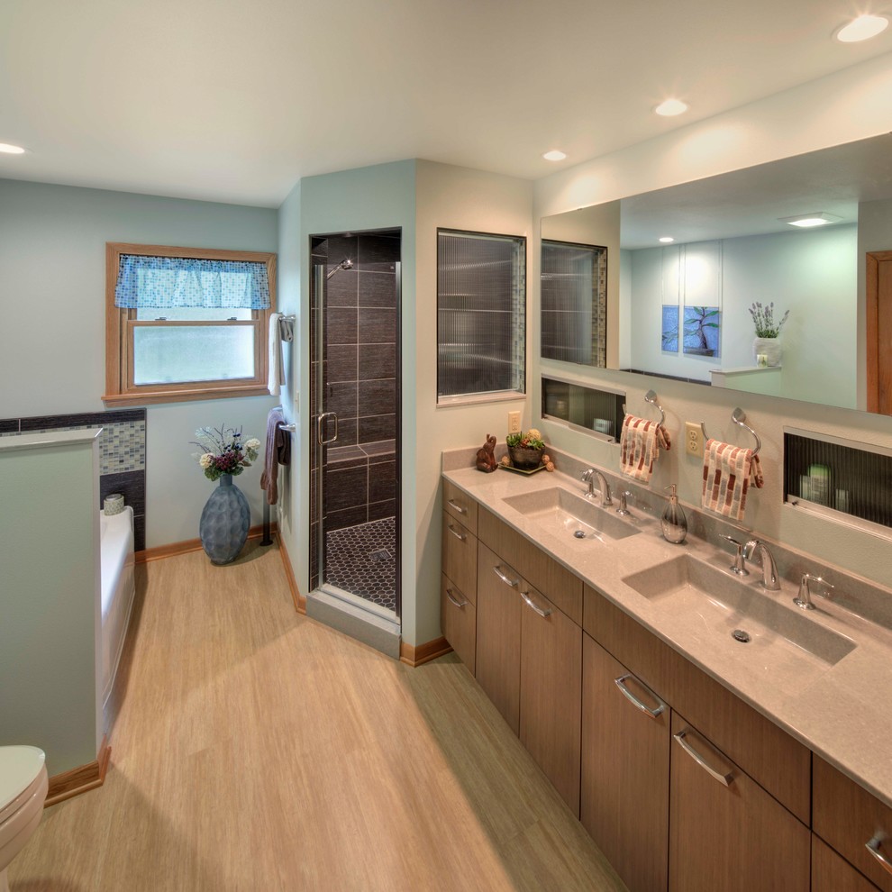 Design ideas for a mid-sized transitional master bathroom in Milwaukee with flat-panel cabinets, medium wood cabinets, a drop-in tub, a corner shower, a one-piece toilet, brown tile, porcelain tile, green walls, vinyl floors, an integrated sink, onyx benchtops, brown floor, a hinged shower door and grey benchtops.