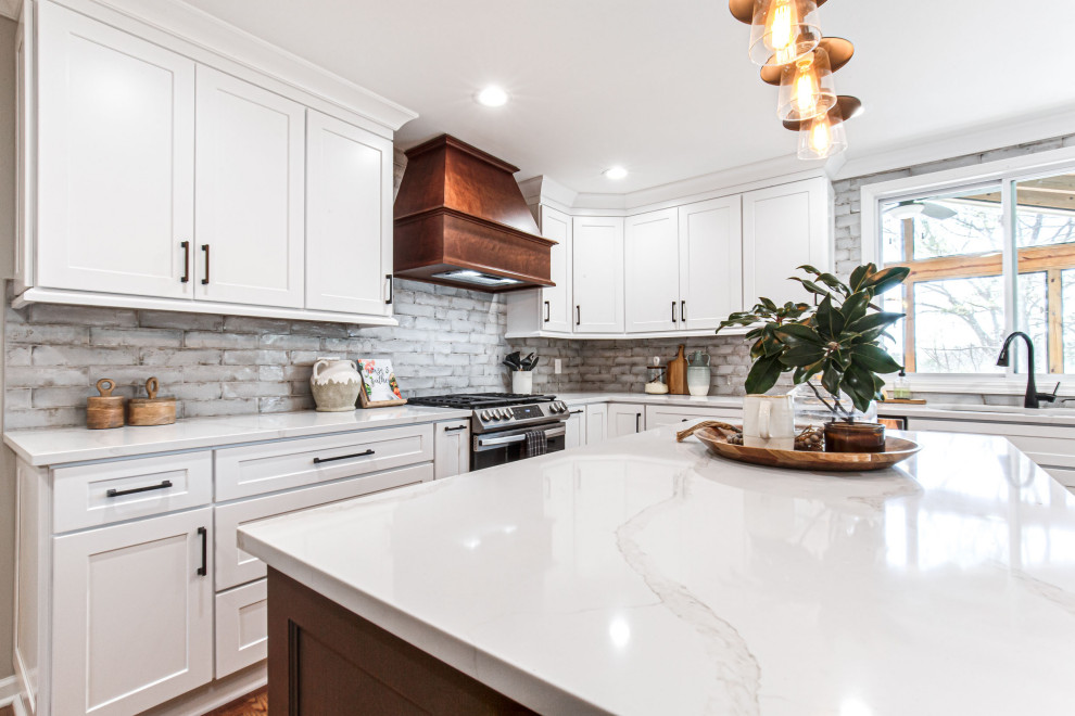 Mid-sized farmhouse u-shaped medium tone wood floor and brown floor enclosed kitchen photo in Atlanta with an undermount sink, shaker cabinets, white cabinets, quartz countertops, gray backsplash, subway tile backsplash, stainless steel appliances, an island and white countertops