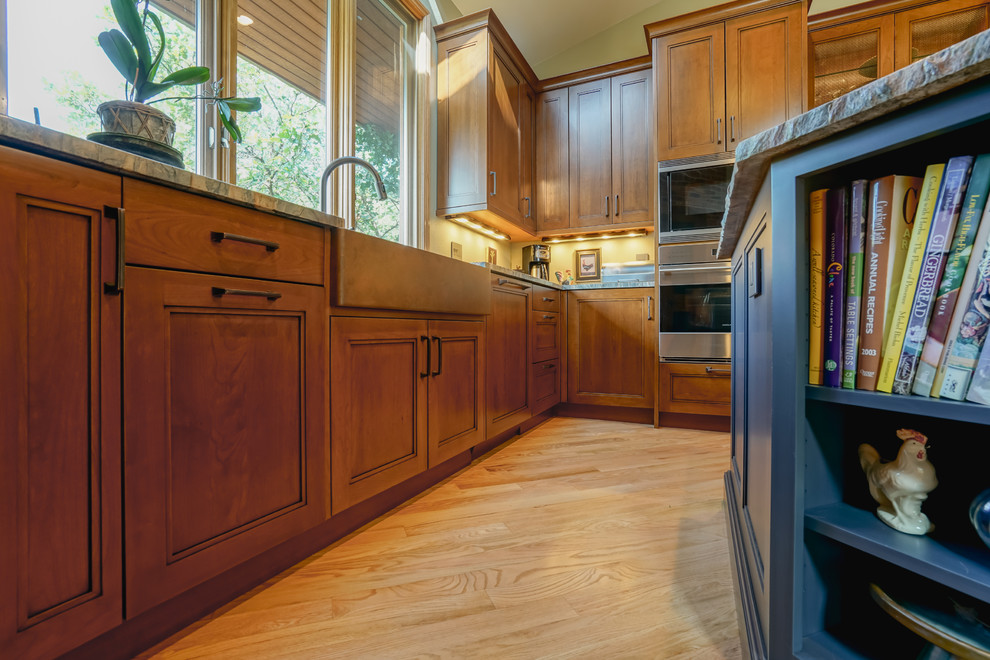 Inspiration for a mid-sized transitional medium tone wood floor and brown floor kitchen remodel in Denver with a farmhouse sink, recessed-panel cabinets, medium tone wood cabinets, granite countertops, paneled appliances and an island