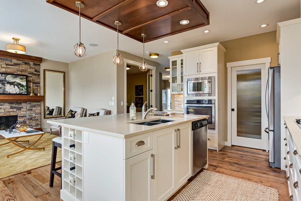 Mid-sized transitional medium tone wood floor kitchen photo in Calgary with a double-bowl sink, shaker cabinets, stainless steel appliances and an island