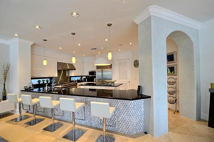 This is an example of a large contemporary galley eat-in kitchen in Los Angeles with a drop-in sink, flat-panel cabinets, white cabinets, granite benchtops, black splashback, glass tile splashback, stainless steel appliances, marble floors and with island.