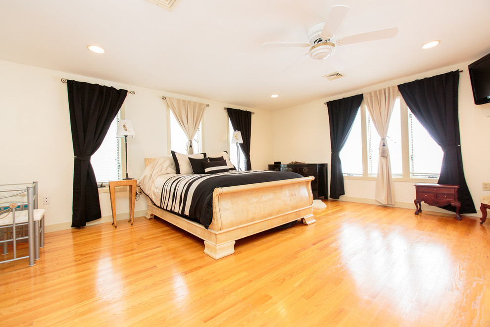This is an example of a large transitional master bedroom in Boston with white walls and medium hardwood floors.