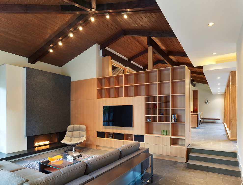 This is an example of a large modern open concept living room in DC Metro with slate floors, a standard fireplace, a stone fireplace surround and a built-in media wall.