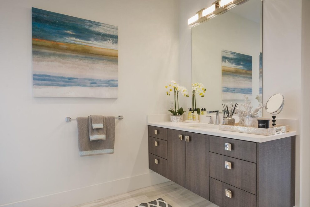 Design ideas for a contemporary master bathroom in Miami with flat-panel cabinets, medium wood cabinets, a freestanding tub, a curbless shower, white tile, white walls, marble floors, solid surface benchtops, white floor and a hinged shower door.