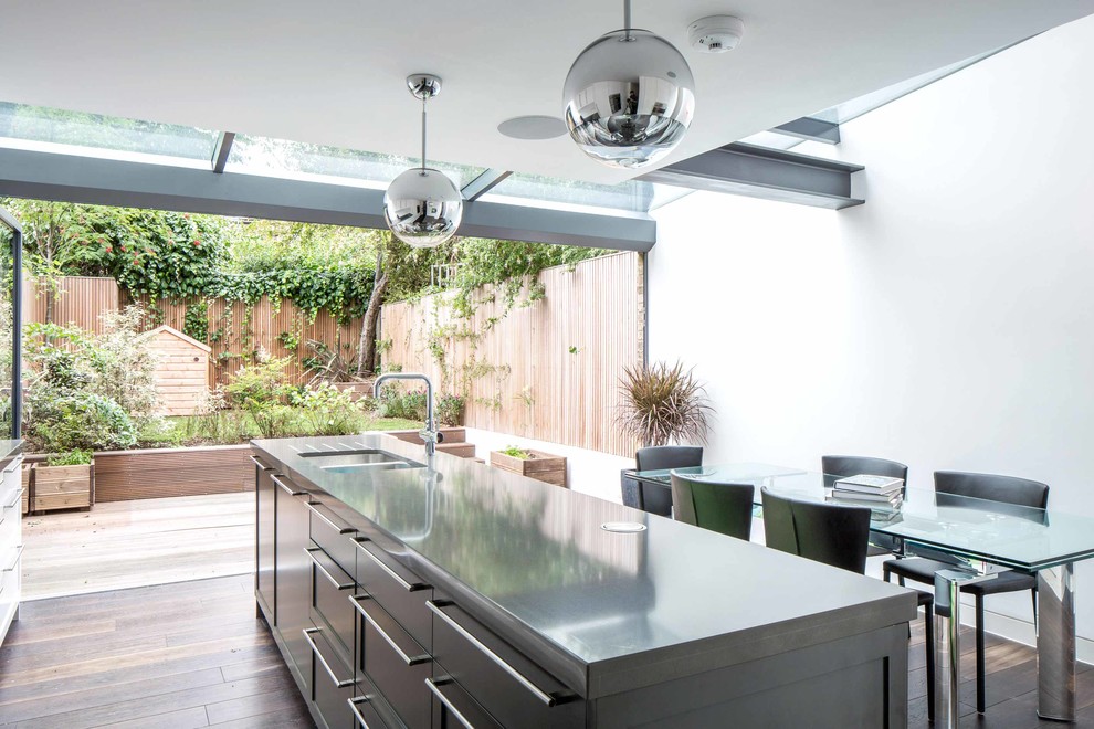 Inspiration for a mid-sized contemporary single-wall eat-in kitchen in London with an integrated sink, shaker cabinets, grey cabinets, stainless steel benchtops, panelled appliances, dark hardwood floors, with island and brown floor.