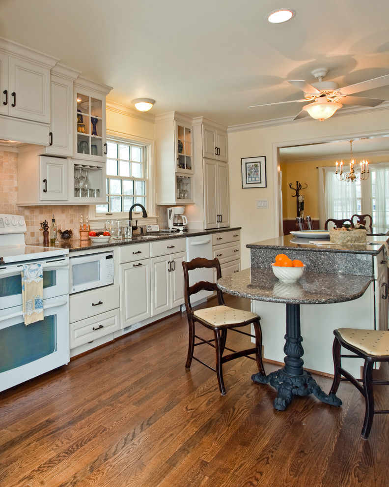 Inspiration for a mid-sized traditional galley open plan kitchen in DC Metro with raised-panel cabinets, white cabinets, quartz benchtops, beige splashback, terra-cotta splashback, white appliances, medium hardwood floors, with island and an undermount sink.
