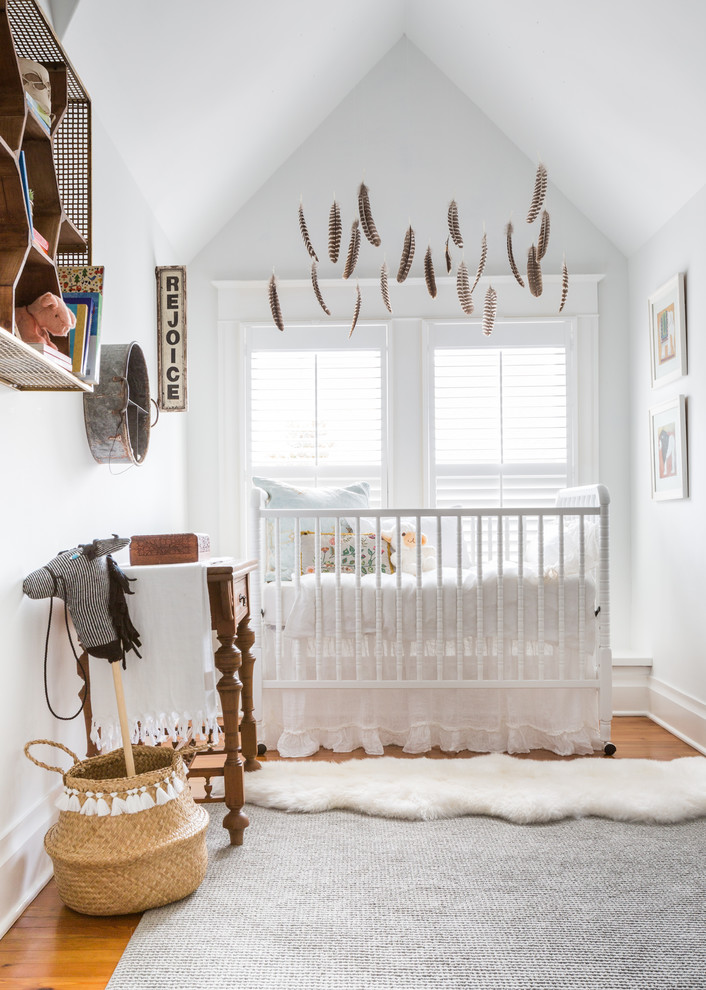 Mid-sized eclectic gender-neutral nursery in Houston with white walls, medium hardwood floors and brown floor.