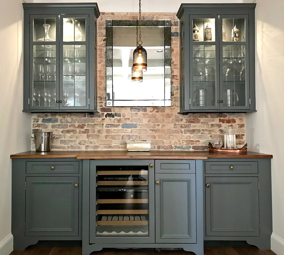 Mid-sized traditional single-wall wet bar in Philadelphia with no sink, recessed-panel cabinets, grey cabinets, wood benchtops, multi-coloured splashback, brick splashback, dark hardwood floors, brown floor and brown benchtop.