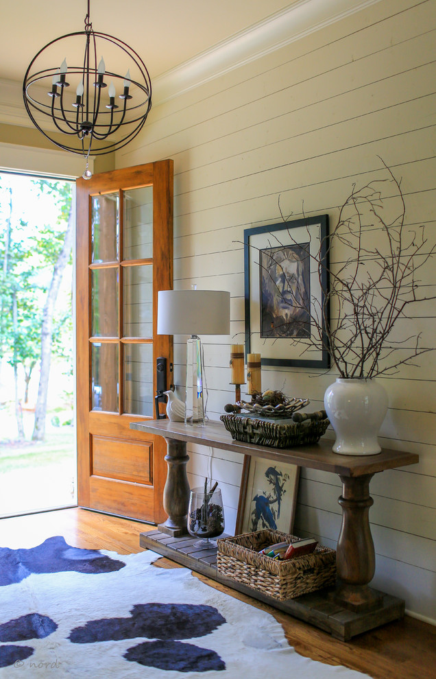 Example of a mid-sized mountain style medium tone wood floor foyer design with white walls and a medium wood front door