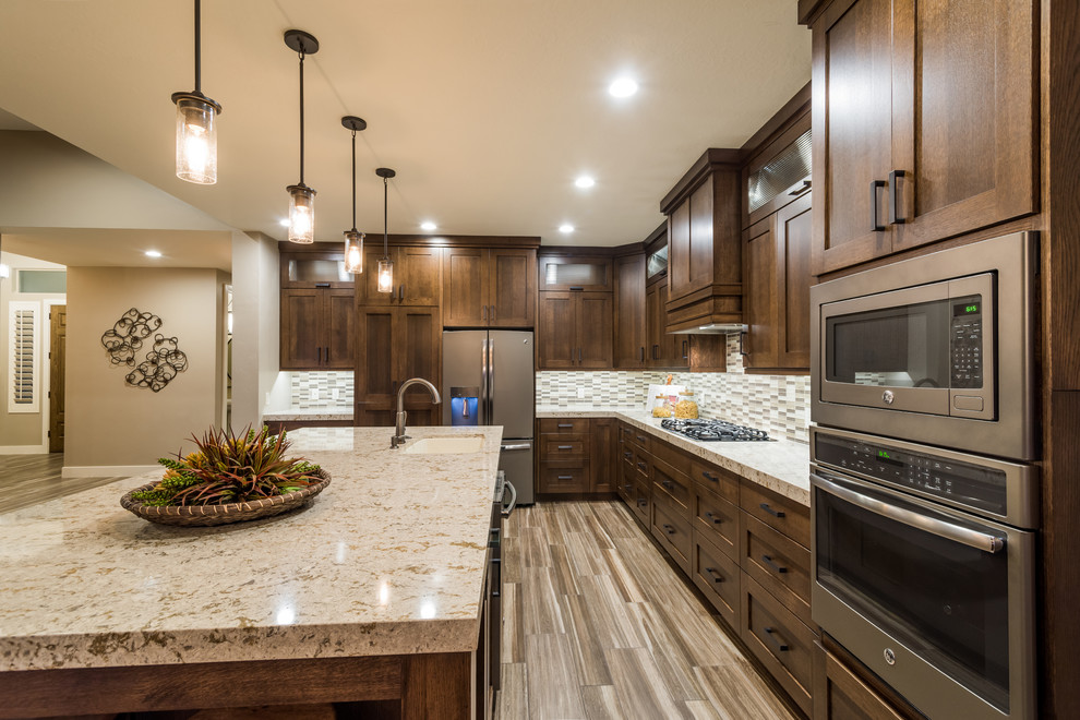 This is an example of a large country l-shaped eat-in kitchen in Salt Lake City with an undermount sink, shaker cabinets, dark wood cabinets, granite benchtops, grey splashback, matchstick tile splashback, stainless steel appliances, porcelain floors and with island.